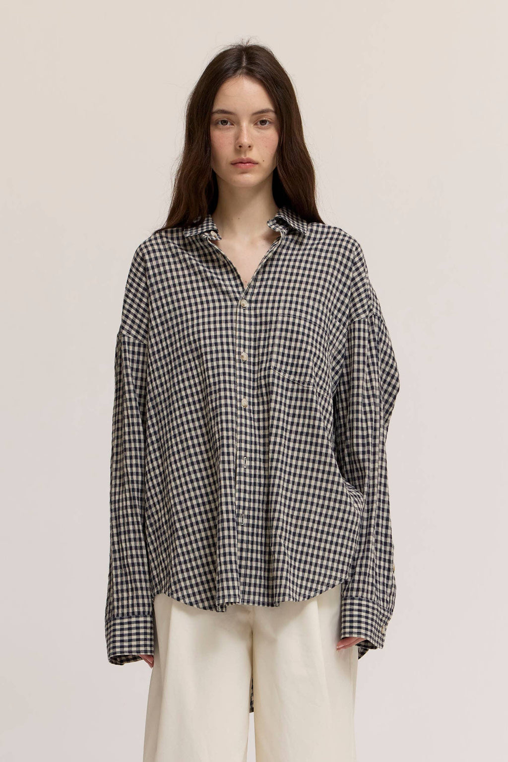 Woman wearing a black and white checkered shirt on a plain background