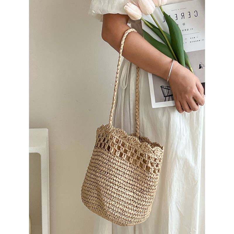 Woven handbag held by a person with a blurred background