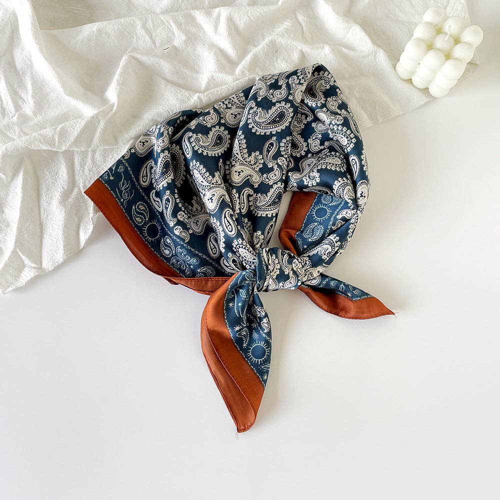 Blue paisley headscarf with rust-colored edges on a white background