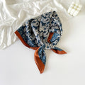 Blue paisley headscarf with rust-colored edges on a white background