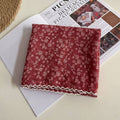Folded red floral fabric handkerchief on a newspaper background