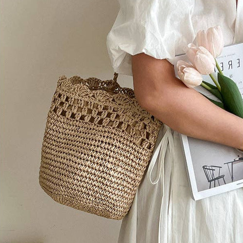 Person holding a woven bag and a magazine with tulips.