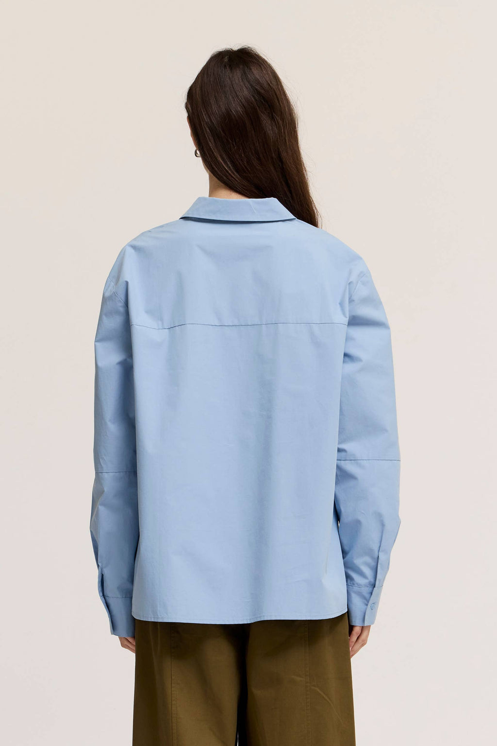 Person wearing a light blue shirt with a neutral background