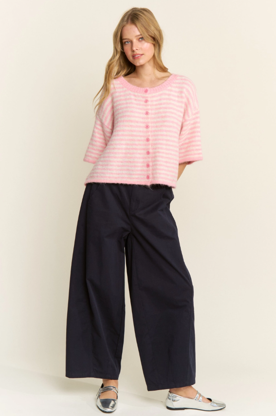 Woman wearing a pink striped shirt and navy pants against a white background