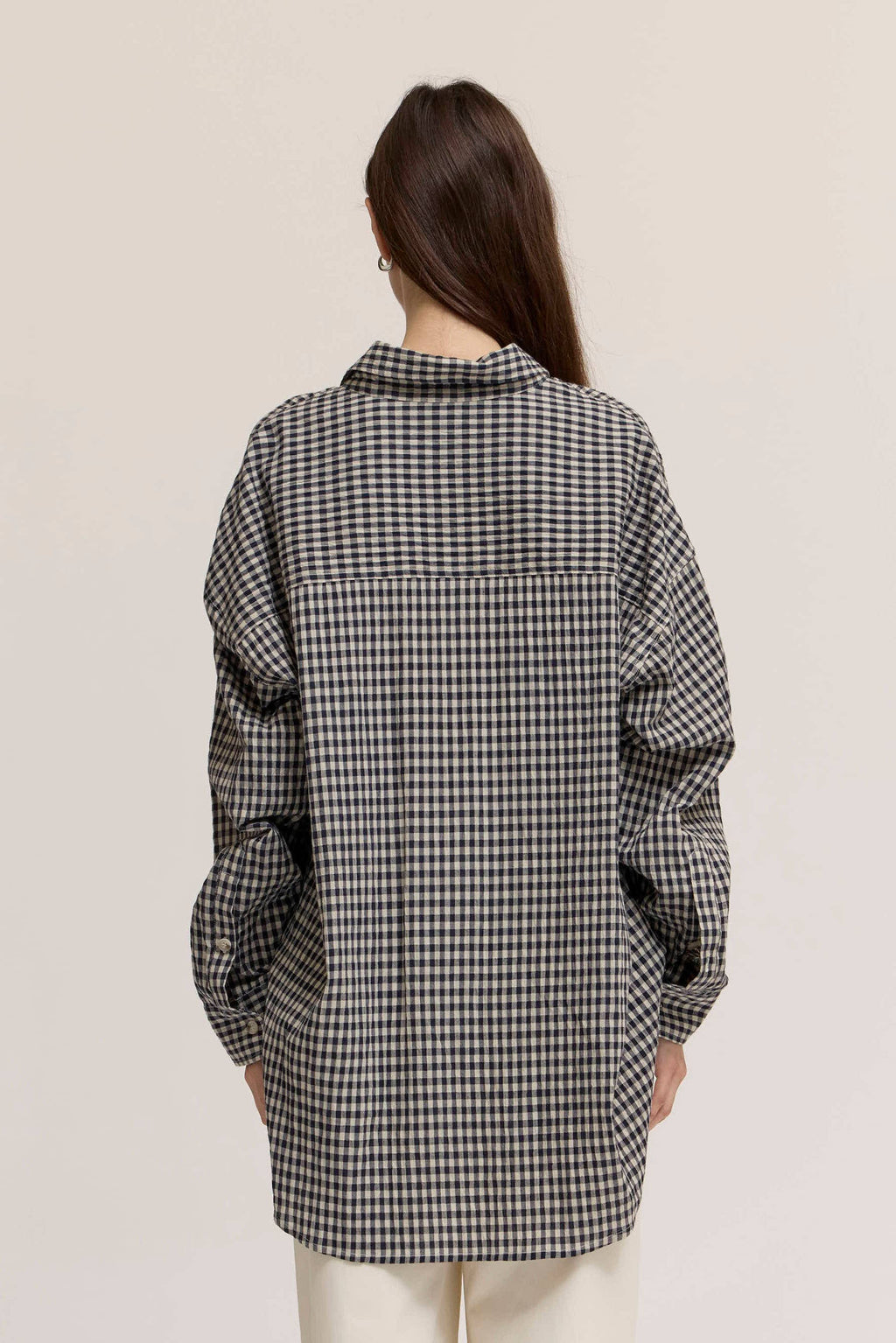 Person wearing a black and white checkered shirt against a plain background