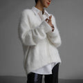 Person wearing a white fluffy cardigan over a white shirt and leather pants