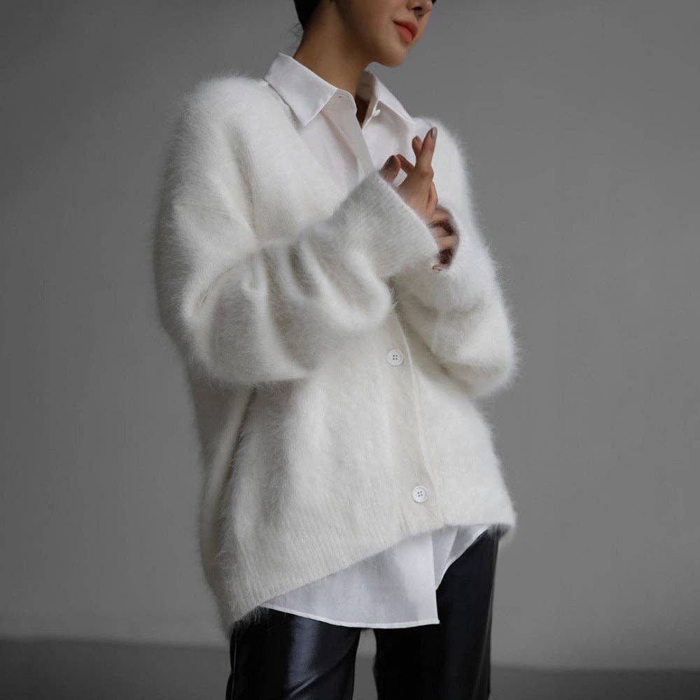 Person wearing a white fluffy cardigan over a white shirt and leather pants
